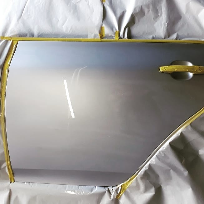 Puerta de un auto enmascarada recién pintada con un color gris metalizado igual al de fábrica.
