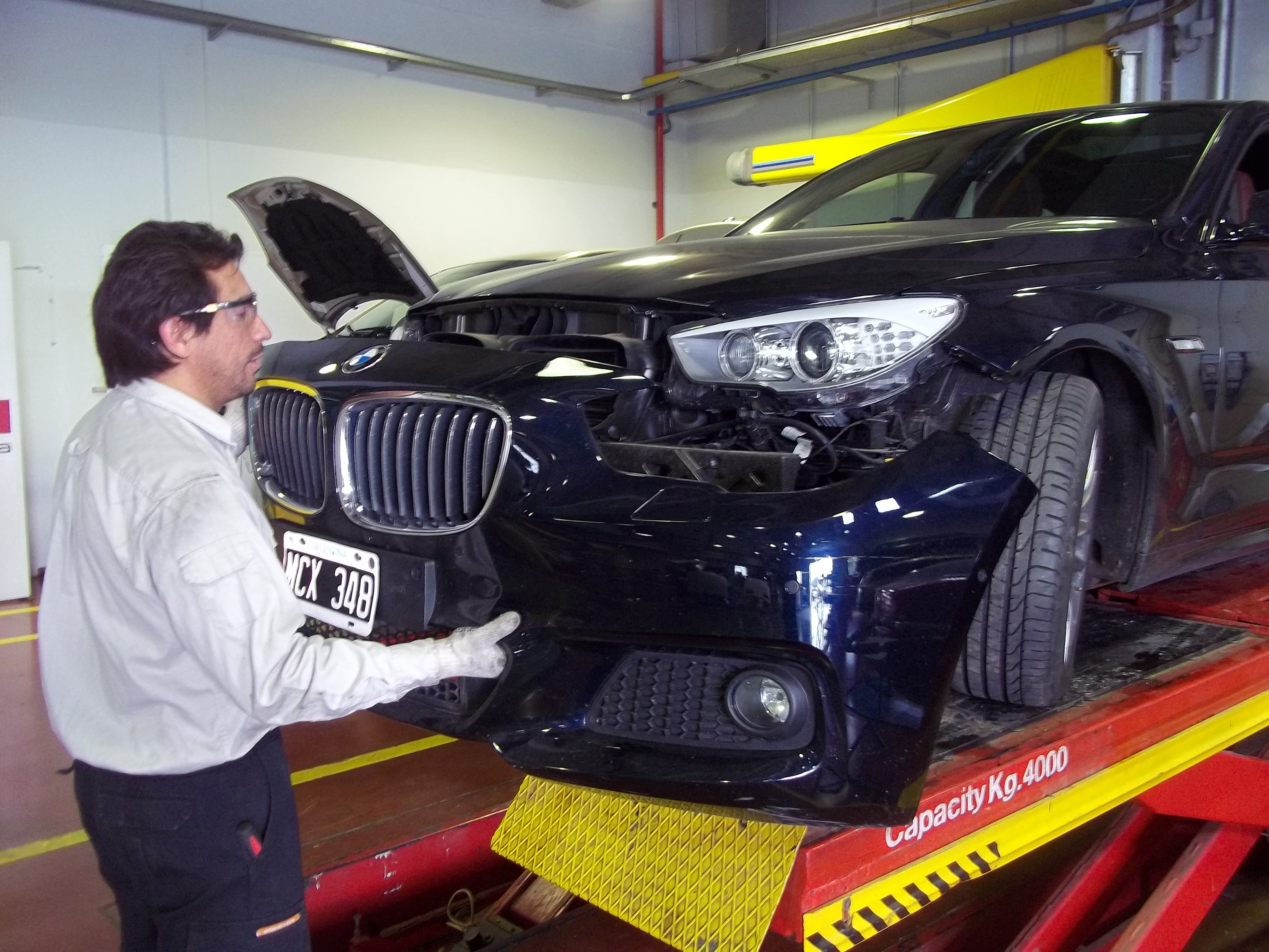 Persona desmontando el paragolpes de un auto.