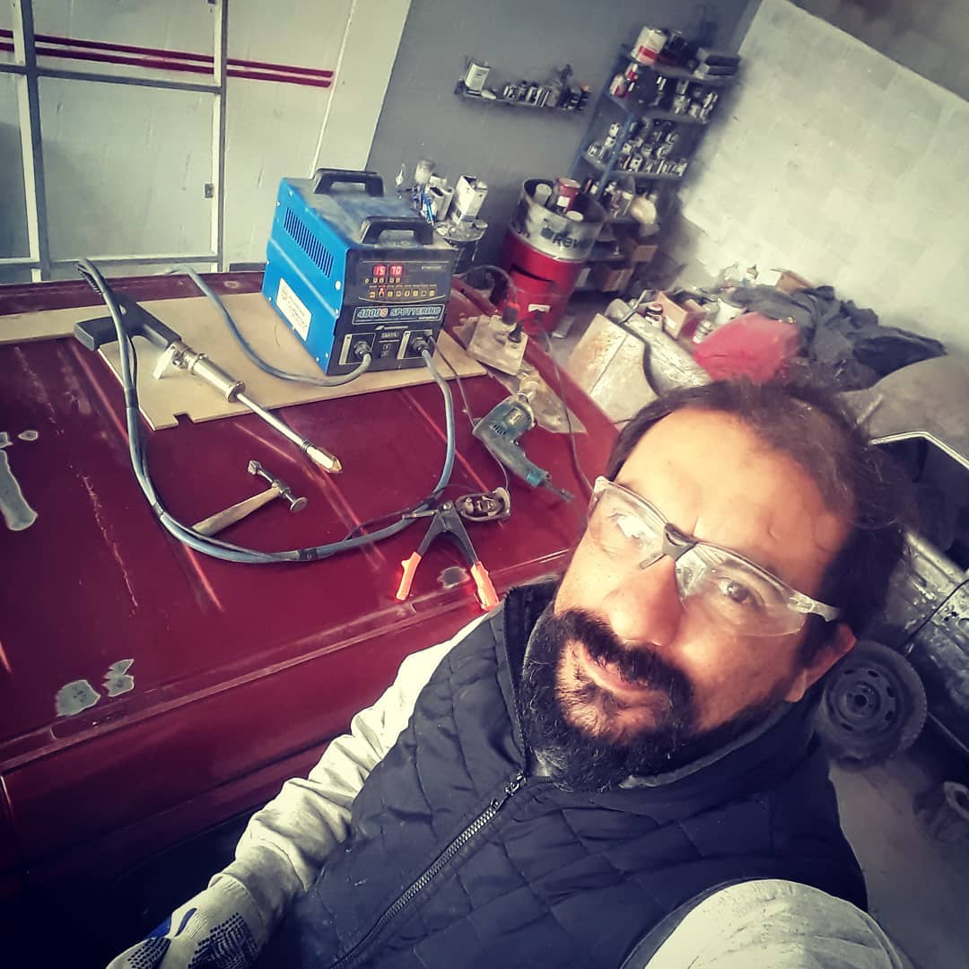 Persona con una soldadora MIG por iniciar la reparación del techo de un auto.